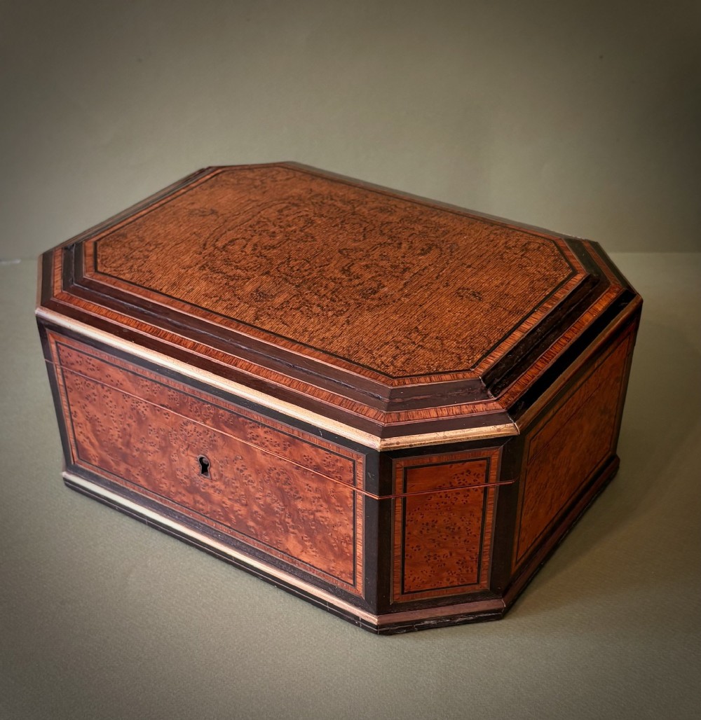 An open octagonal antique walnut marquetry sewing box featuring a blue velvet fitted interior filled with carved tools and a padded silk lid lining. View II