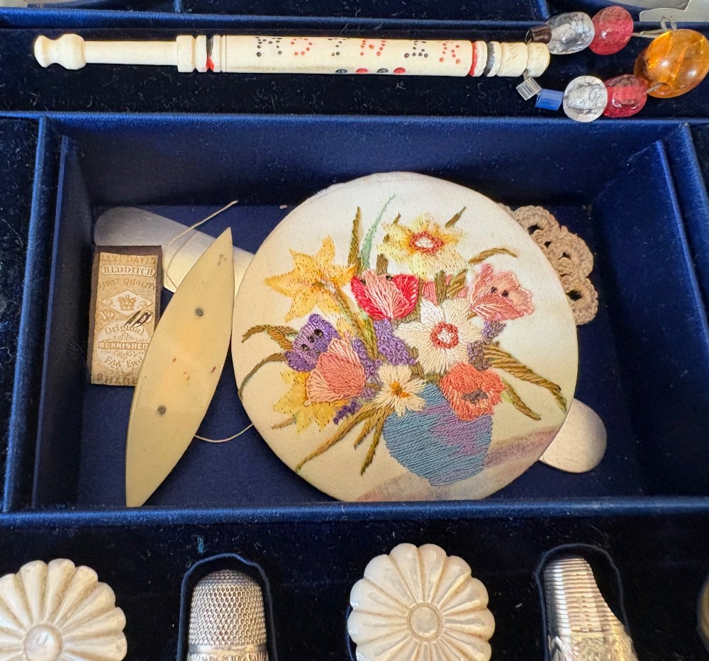 An open octagonal antique walnut marquetry sewing box featuring a blue velvet fitted interior filled with carved tools and a padded silk lid lining. View V