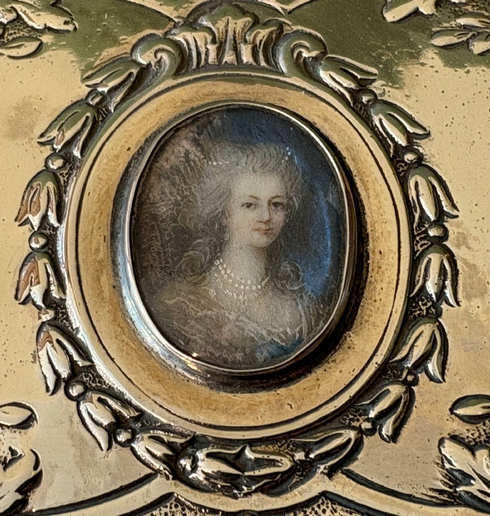 A rectangular silver snuff box decorated with floral relief work and a central oval portrait miniature of a woman. View II