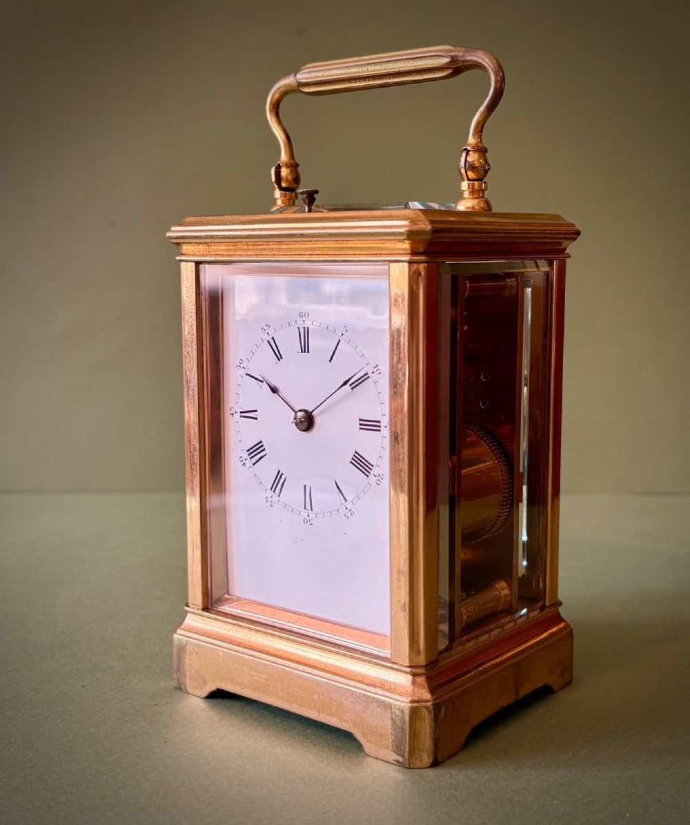 A 19th-century French gilt brass carriage clock with bevelled glass side panels, an enamel dial with Roman numerals, and a hinged top carrying handle.