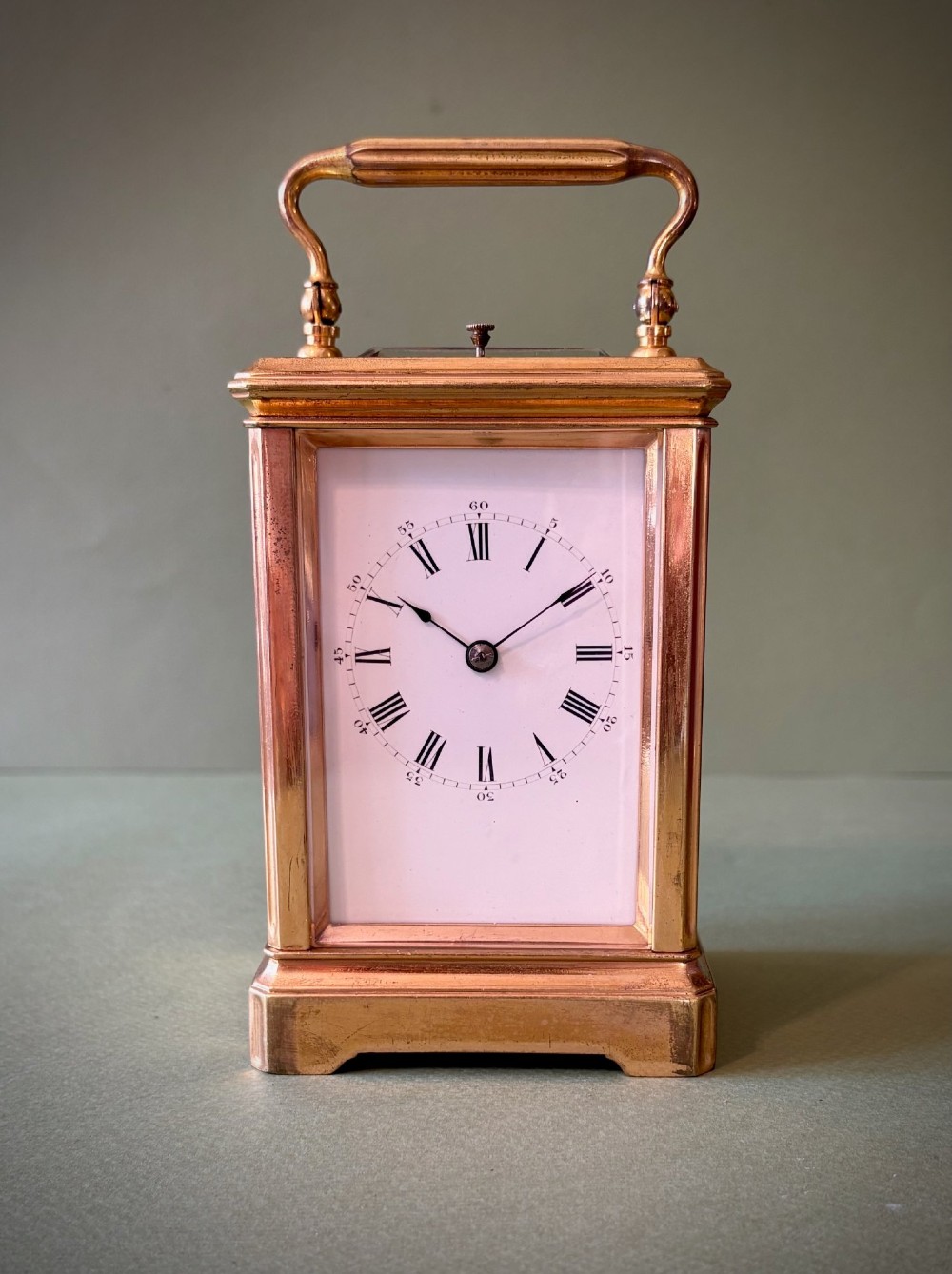 A 19th-century French gilt brass carriage clock with bevelled glass side panels, an enamel dial with Roman numerals, and a hinged top carrying handle. View II