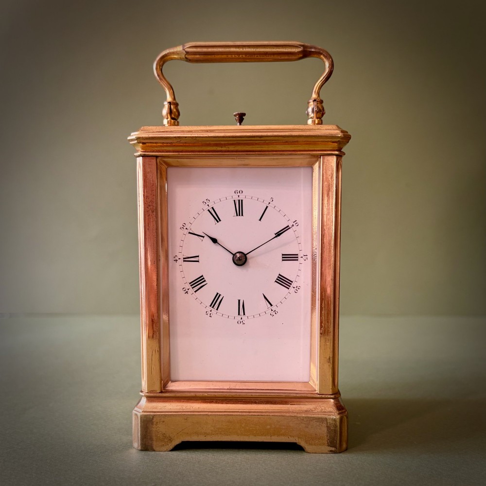 A 19th-century French gilt brass carriage clock with bevelled glass side panels, an enamel dial with Roman numerals, and a hinged top carrying handle. View VI