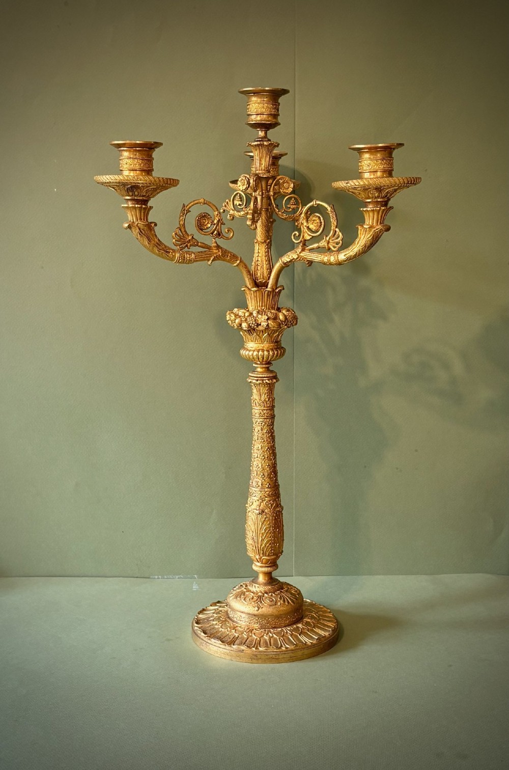 A pair of five-light gilt bronze ormolu candelabra featuring scrolling branches, acanthus leaf casting, and circular gadrooned bases. View II