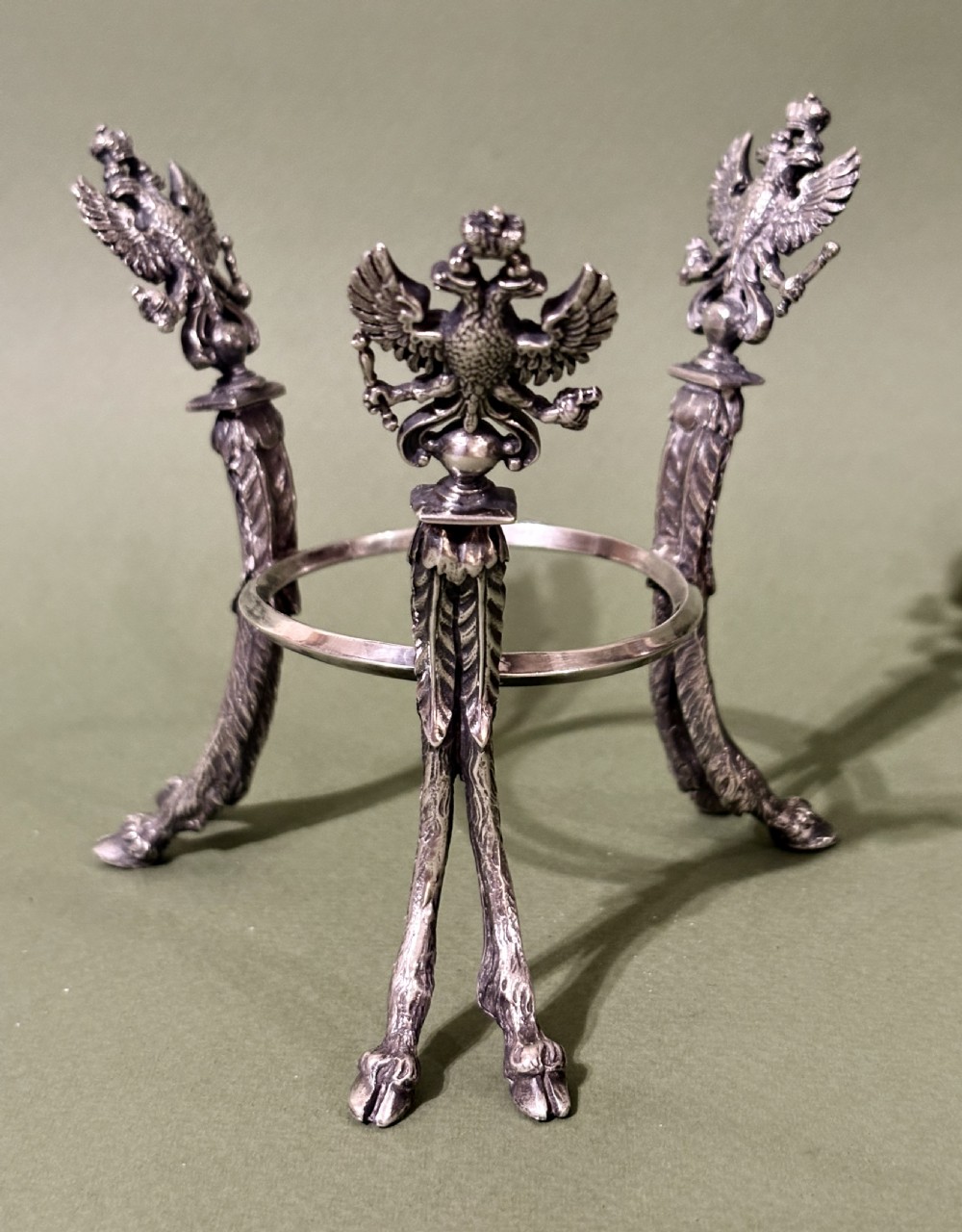 A Russian silver egg decorated with polychrome floral enamel scrolls and set with cabochon stones, resting on a tripod silver stand with hoofed feet. View IX
