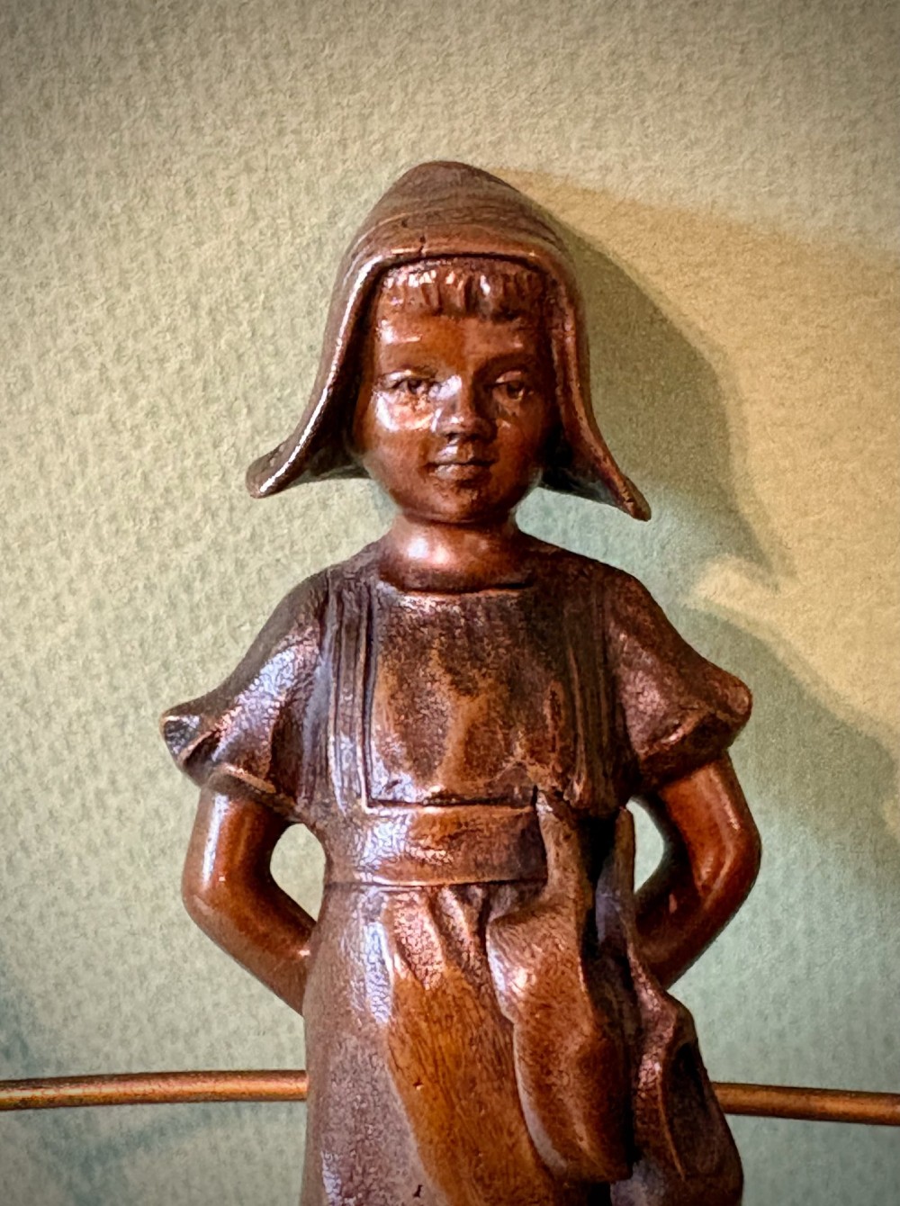 A patinated bronze figurine depicting a young farmer girl holding a rake, mounted on a dark marble pedestal base. View II