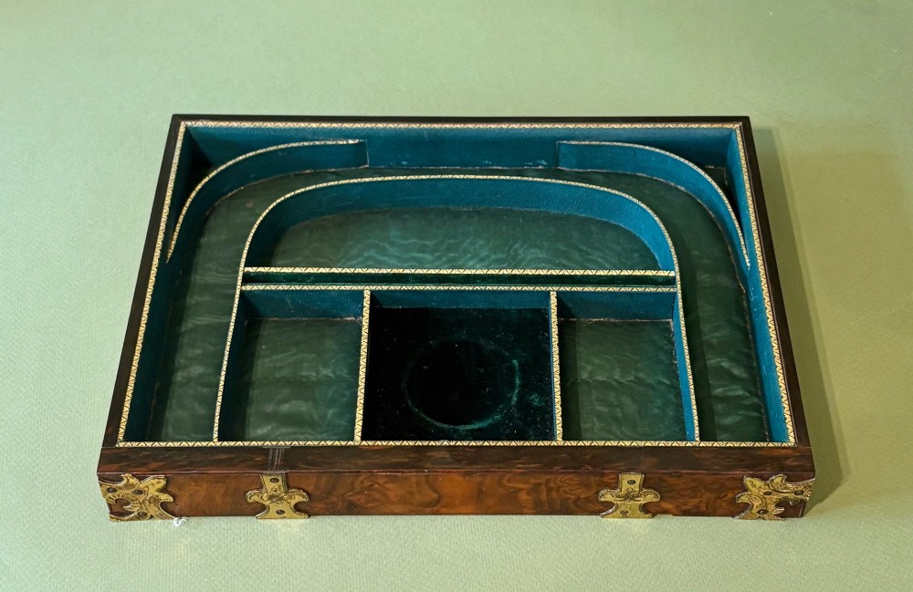 An open Victorian burr walnut dressing case featuring brass mounts, green velvet lining, silver-topped glass jars, vanity tools, and a pull-out lower drawer. View IV