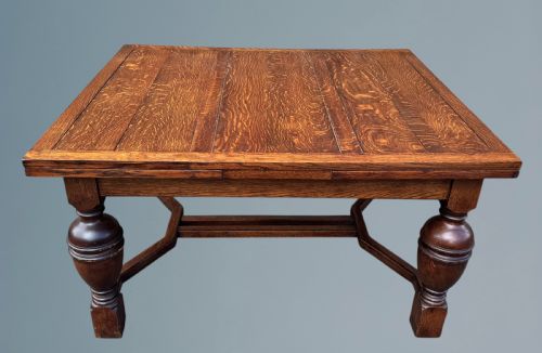 fig 1. A rectangular warm brown oak draw-leaf dining table featuring heavy bulbous turned legs, low stretchers, and a quarter-sawn timber grain top.
