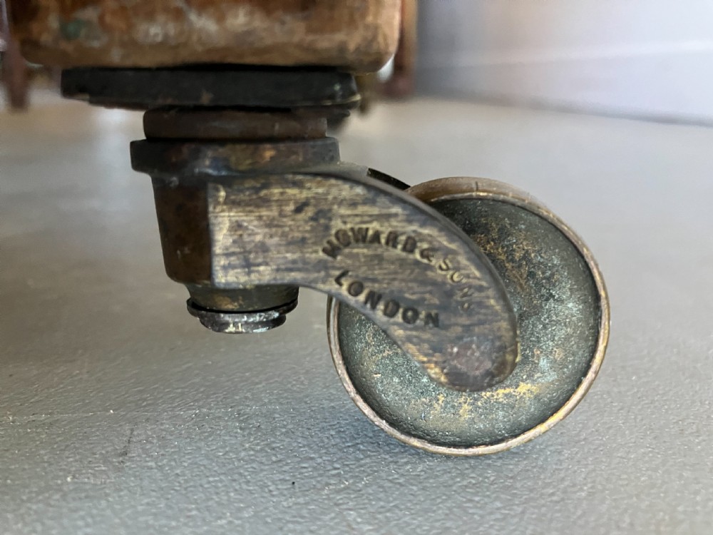 A Victorian button-backed armchair upholstered in a blue and white botanical pattern with turned front legs on brass castors. View VII
