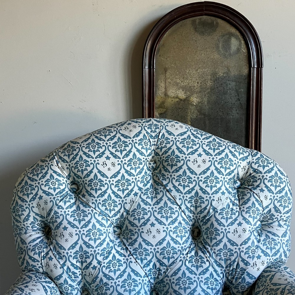 A Victorian button-backed armchair upholstered in a blue and white botanical pattern with turned front legs on brass castors. View VIII
