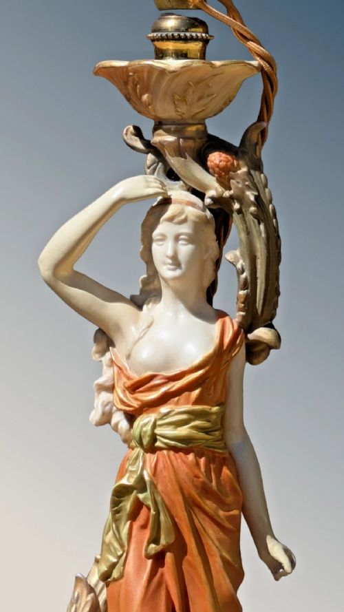 A Royal Worcester porcelain table lamp featuring a sculpted classical female figure in terracotta drapery beneath a pleated white shade. View II
