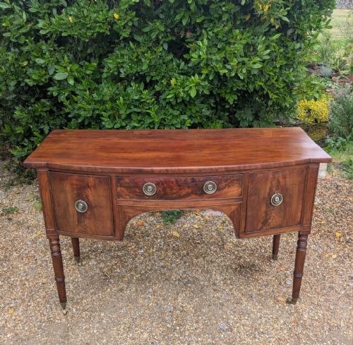 fig 2. A Regency period mahogany sideboard featuring turned legs on brass castors, central drawer, flanking cupboard doors, and circular brass ring handles.