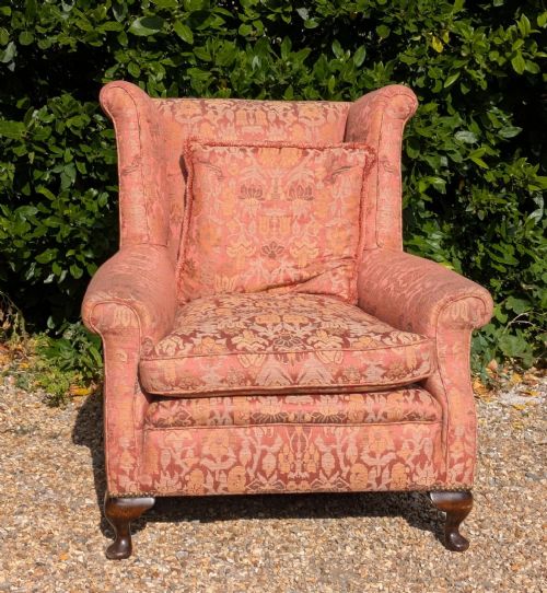 fig 1. An upholstered wingback armchair in terracotta patterned damask fabric with a feather-filled seat cushion and carved timber cabriole legs.