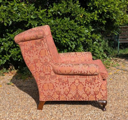 fig 2. An upholstered wingback armchair in terracotta patterned damask fabric with a feather-filled seat cushion and carved timber cabriole legs.