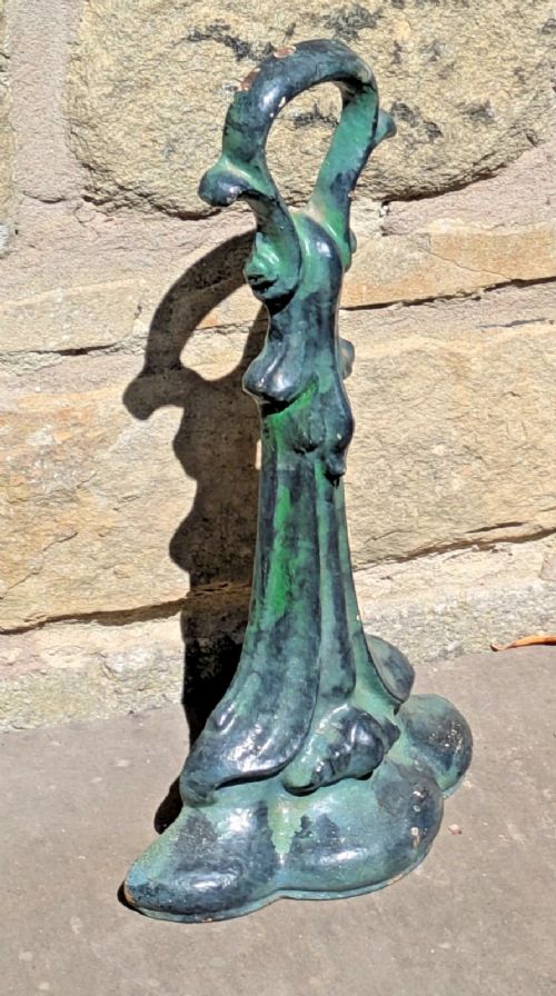 An Art Nouveau cast iron doorstop featuring a vertical stem with organic leaf motifs, a loop handle at the top, and a green patinated finish. View II