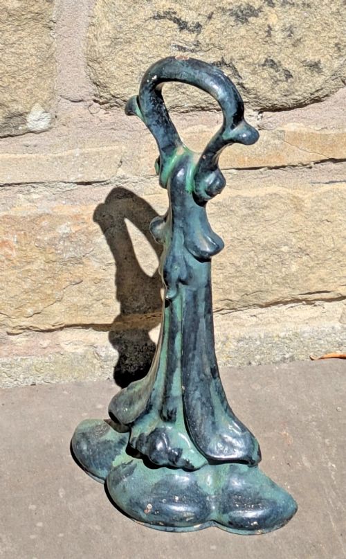 An Art Nouveau cast iron doorstop featuring a vertical stem with organic leaf motifs, a loop handle at the top, and a green patinated finish. View IV