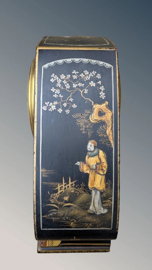 A black lacquered arched mantel clock featuring hand-painted gold Chinoiserie figures and landscapes surrounding a central brass dial. View V