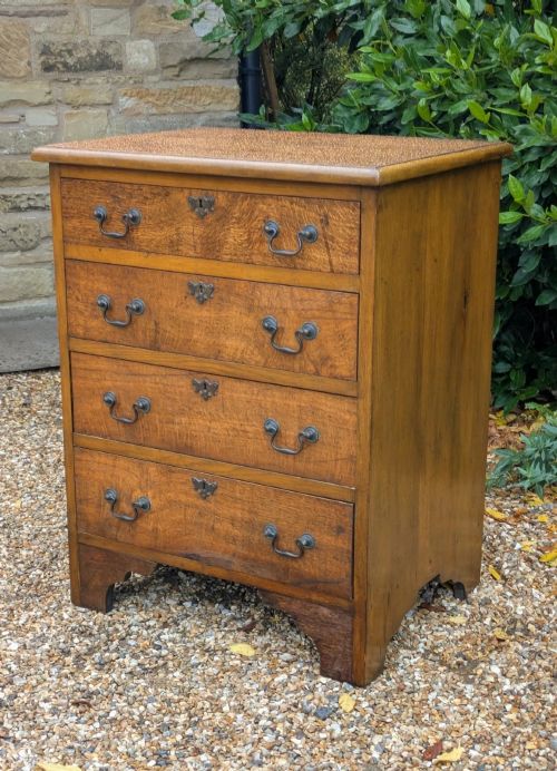 fig 1. A compact oak bachelors chest of drawers featuring four graduated drawers with metal drop handles and keyhole escutcheons on a shaped bracket base.