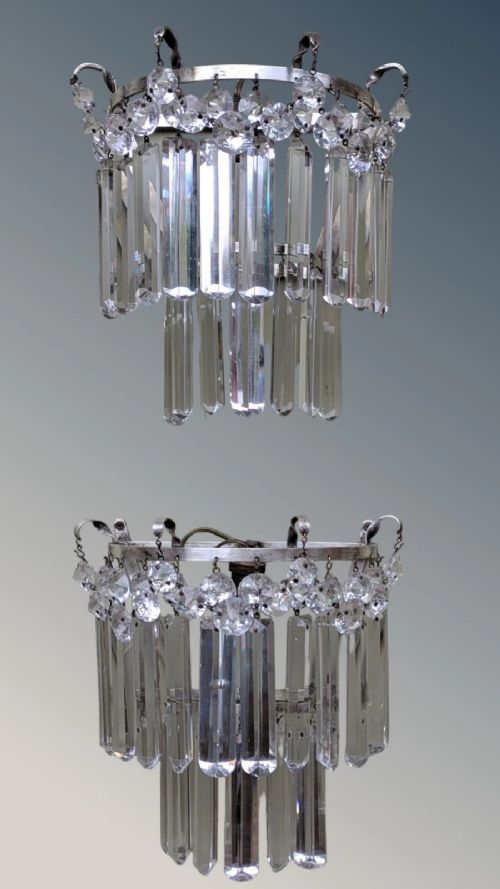 fig 1. A pair of semi-circular wall lights featuring cascading tiers of clear cut crystal rectangular prisms suspended from silver-toned metal frames.