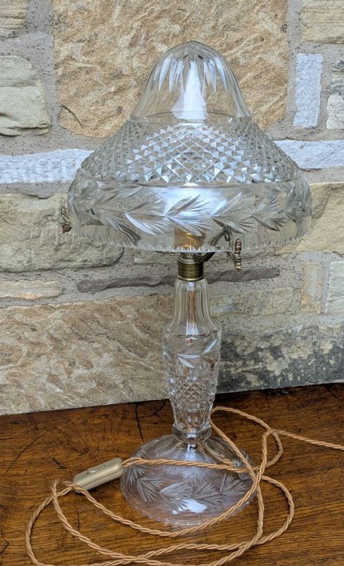 An antique cut crystal table lamp featuring a diamond-cut dome shade, a faceted baluster stem, and brass fittings. View VI