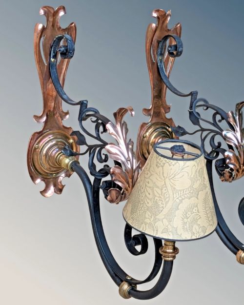 fig 1. A pair of antique Arts and Crafts wall lights featuring shaped copper backplates, hand-forged black wrought iron scrollwork arms, copper leaf accents, and patterned fabric tapered shades.