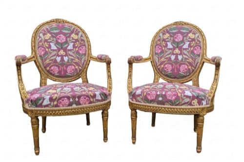 fig 1. A pair of carved giltwood French armchairs featuring oval medallion backs and floral patterned plum-coloured upholstery.