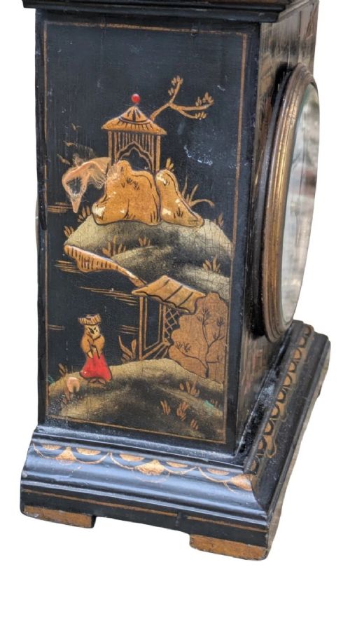A black lacquered Regency style mantel clock decorated with gold hand-painted Chinoiserie landscapes, featuring a white circular dial with Arabic numerals and a top brass handle. View III