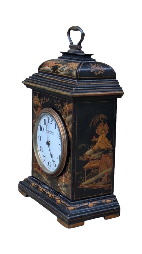 A black lacquered Regency style mantel clock decorated with gold hand-painted Chinoiserie landscapes, featuring a white circular dial with Arabic numerals and a top brass handle. View VII