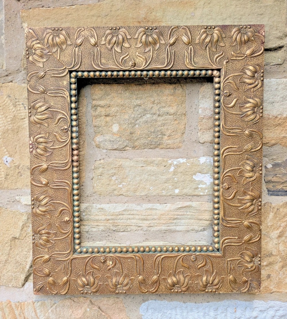 An antique rectangular gold-finished gesso frame decorated with embossed floral motifs and a beaded inner border.