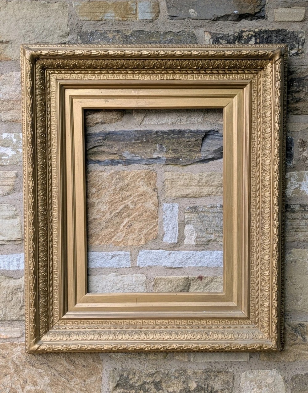A large rectangular Victorian giltwood frame featuring a classical Greek key inner border and relief-moulded leaf patterns along the outer edge.