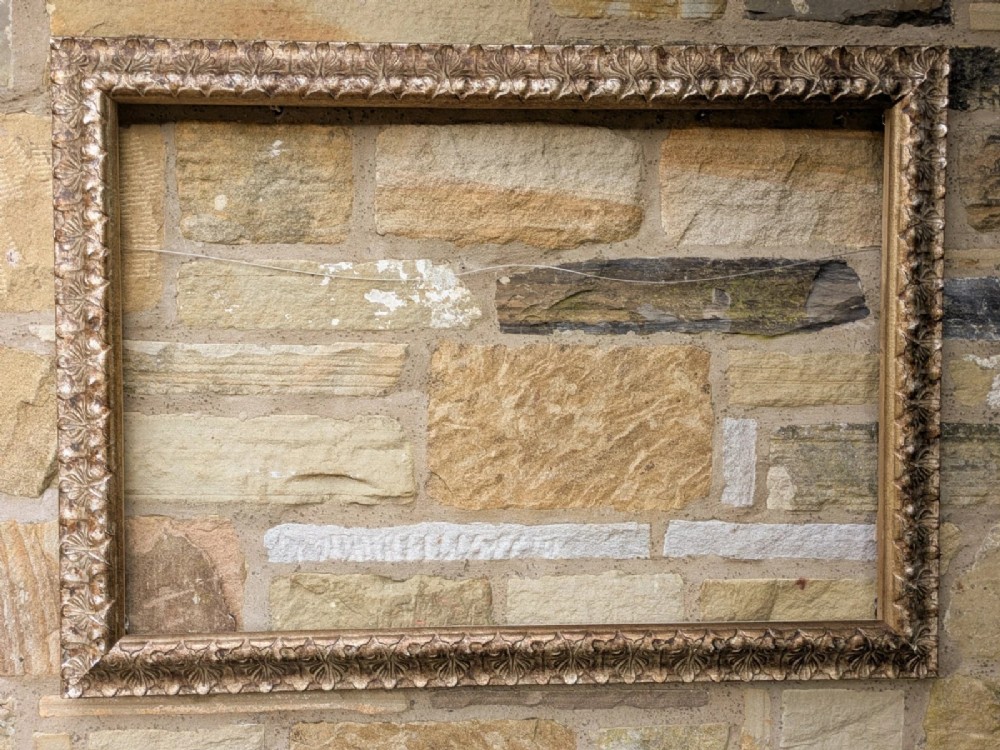 A rectangular silver gilt picture frame featuring repeating carved leaf gesso moulding.