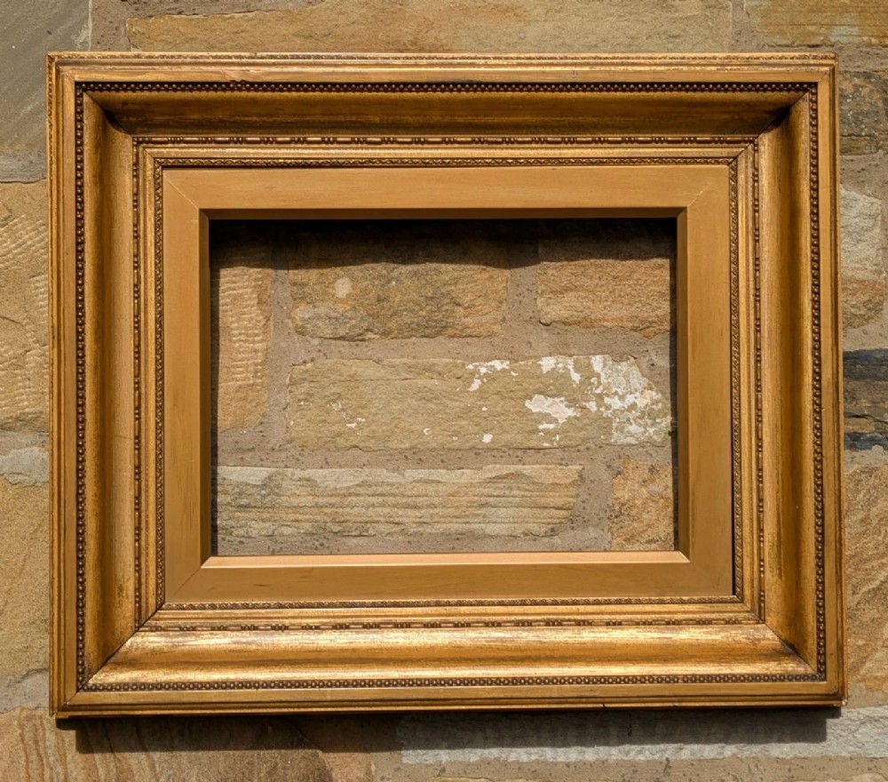 A rectangular Victorian gilt picture frame featuring a deep scoop profile and beaded edge moulding.