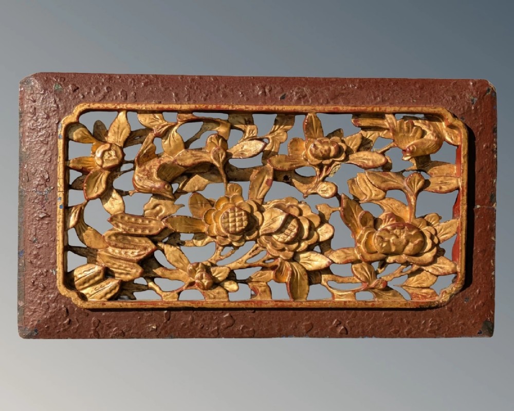 A pair of rectangular Chinese carved wood panels featuring openwork floral and bird motifs finished in gold gilding and framed by textured red lacquer borders. View II