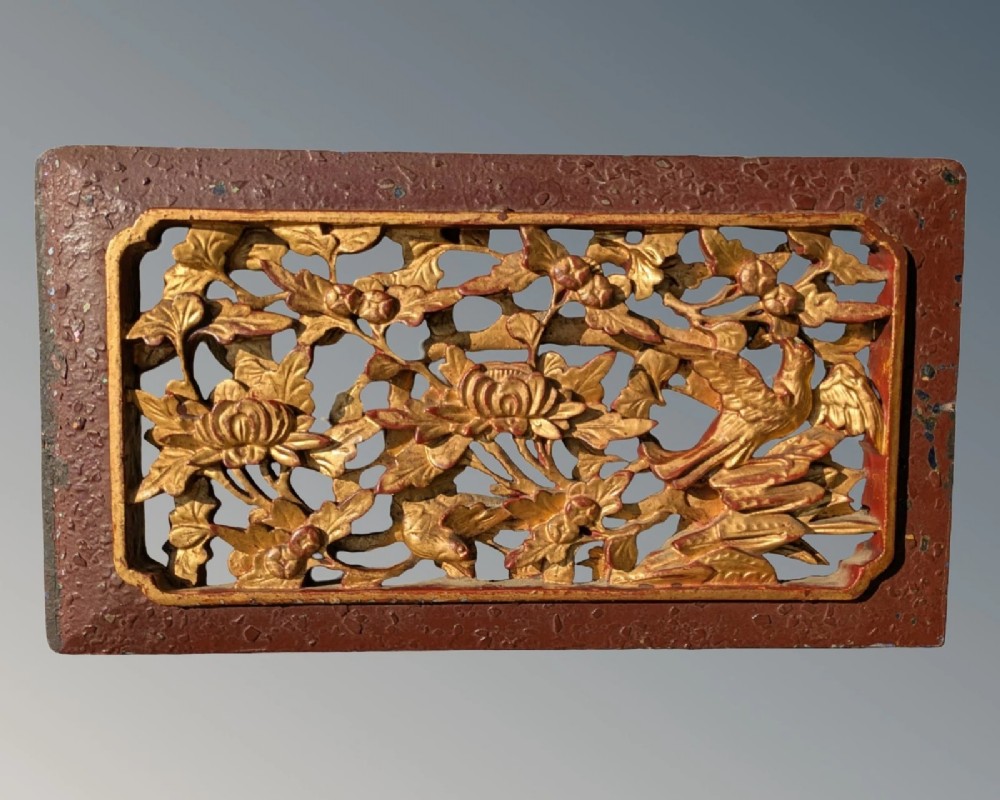A pair of rectangular Chinese carved wood panels featuring openwork floral and bird motifs finished in gold gilding and framed by textured red lacquer borders. View III