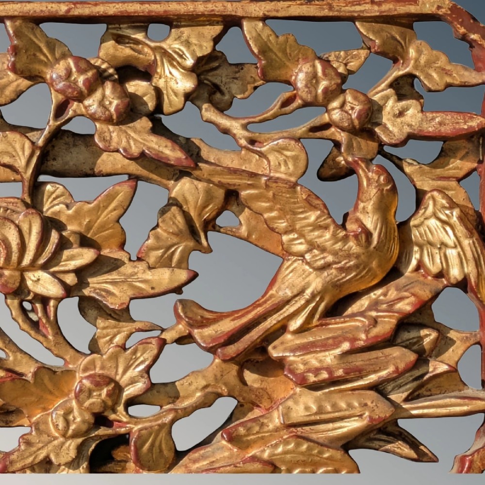 A pair of rectangular Chinese carved wood panels featuring openwork floral and bird motifs finished in gold gilding and framed by textured red lacquer borders. View IV