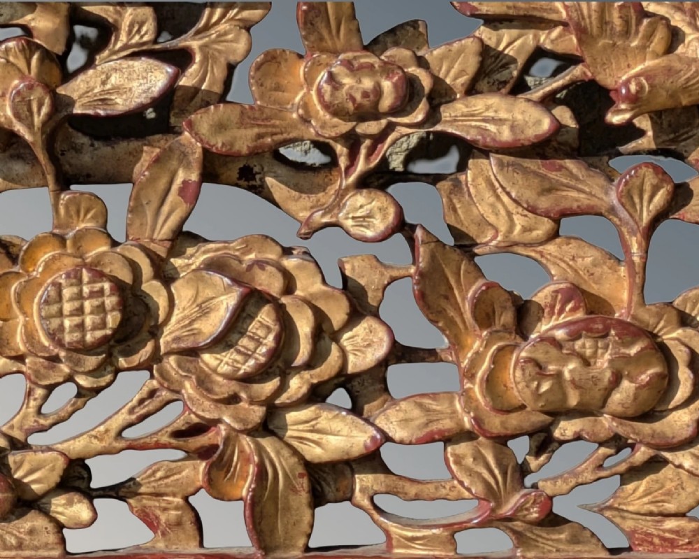 A pair of rectangular Chinese carved wood panels featuring openwork floral and bird motifs finished in gold gilding and framed by textured red lacquer borders. View V