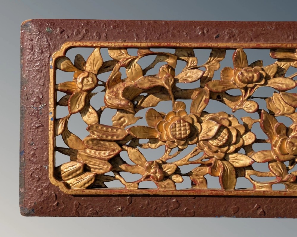 A pair of rectangular Chinese carved wood panels featuring openwork floral and bird motifs finished in gold gilding and framed by textured red lacquer borders. View VI