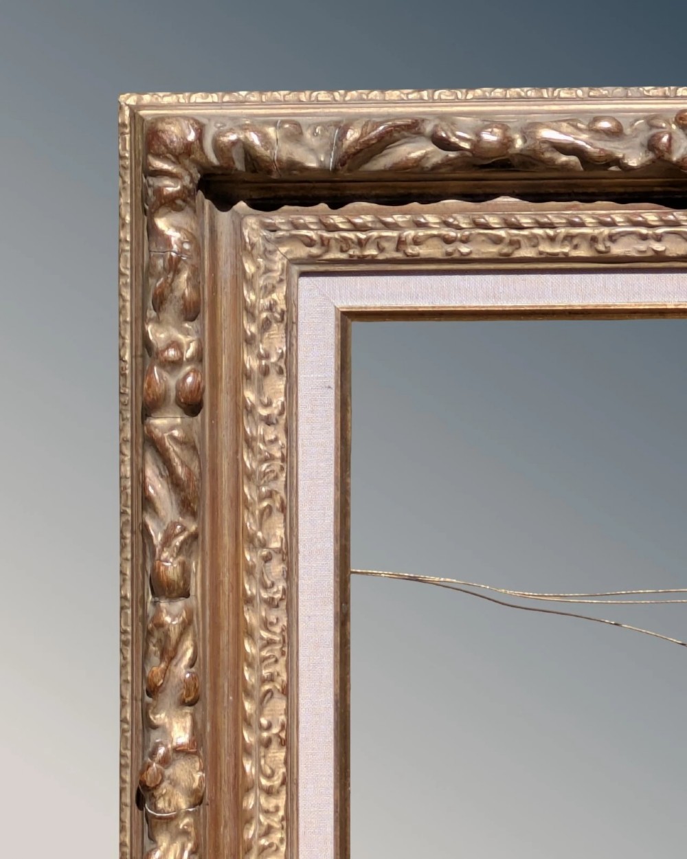 A rectangular carved gilt wood picture frame with an inner neutral linen slip and a central brass plaque along the lower edge. View IV