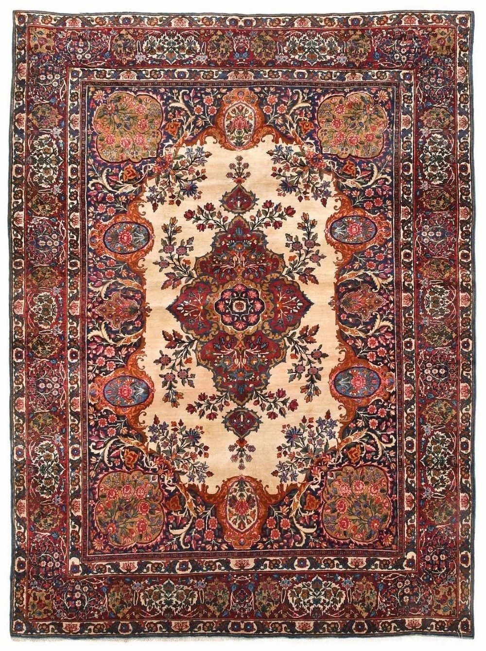 An antique room-sized Kirman Persian carpet featuring a complex central floral medallion on an ivory field surrounded by floral borders in red, navy blue, and gold.