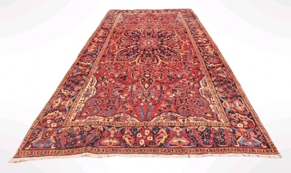 An antique hand-knotted Ahar Heriz wool carpet featuring a large central floral medallion surrounded by detailed vine motifs in rust red, navy blue, and ivory tones. View II