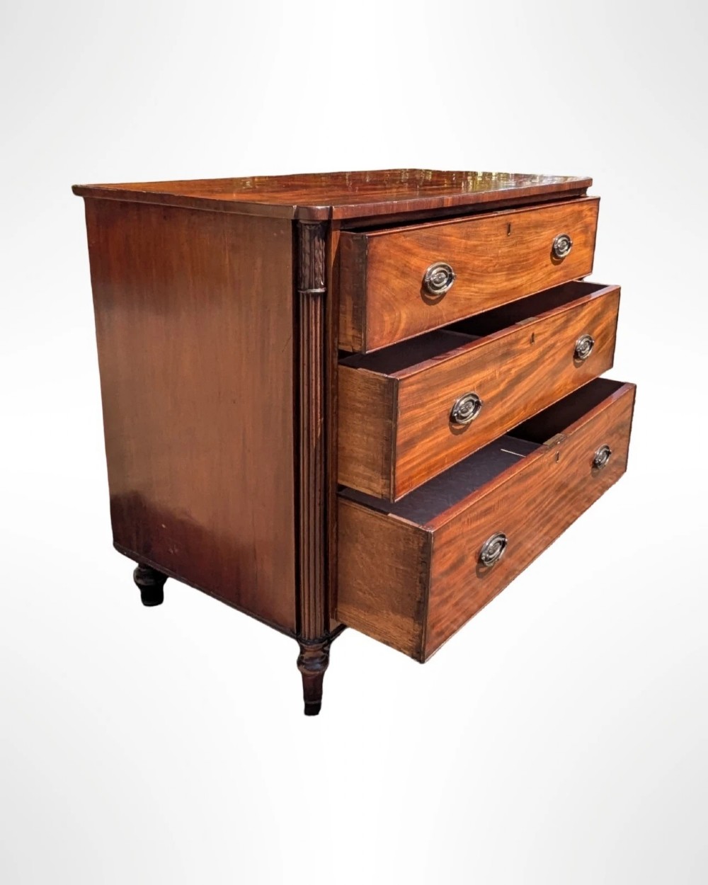 A George III mahogany chest of drawers featuring three full-width drawers with oval brass drop handles, reeded side columns, and turned feet. View VI