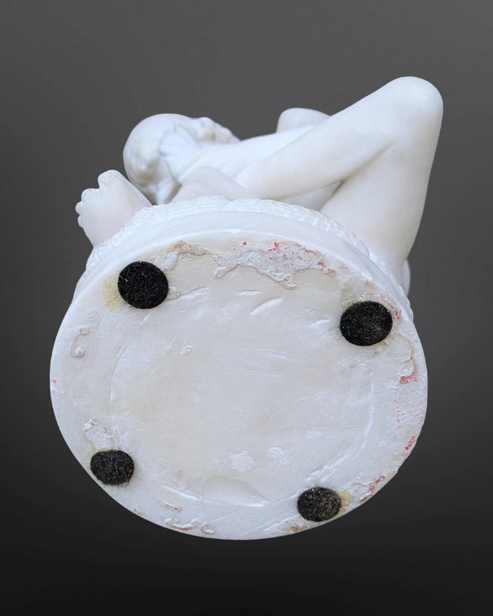 A carved white alabaster sculpture depicting a classical nude youth seated on a tree stump while extracting a thorn from his foot. View V