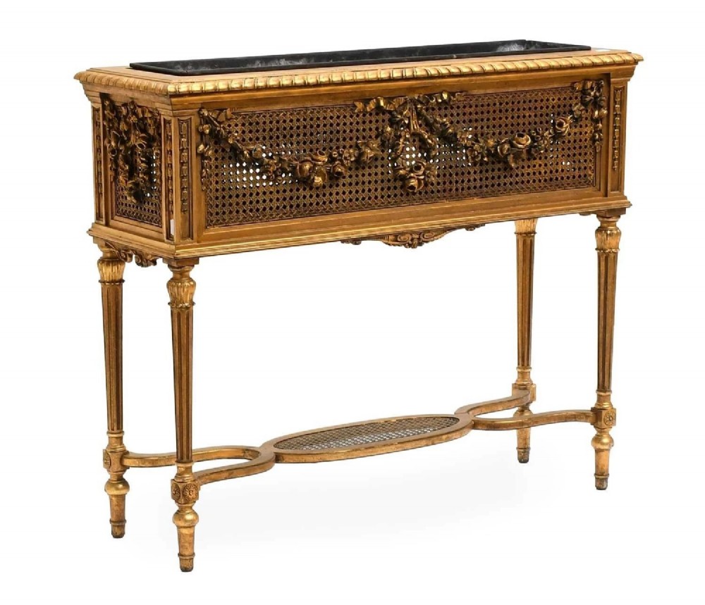 An antique Louis XVI style giltwood and cane jardiniere stand featuring carved floral swags, fluted legs, and an oval stretcher. View II