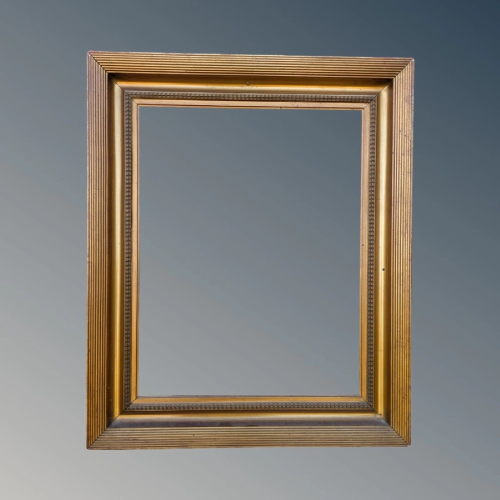 A rectangular antique gilt picture frame featuring a reeded outer border, a deep cove profile, and beaded inner moulding.
