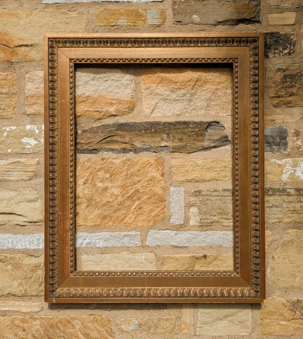 An early twentieth-century rectangular giltwood picture frame featuring classical egg and dart outer moulding and an inner beaded border.