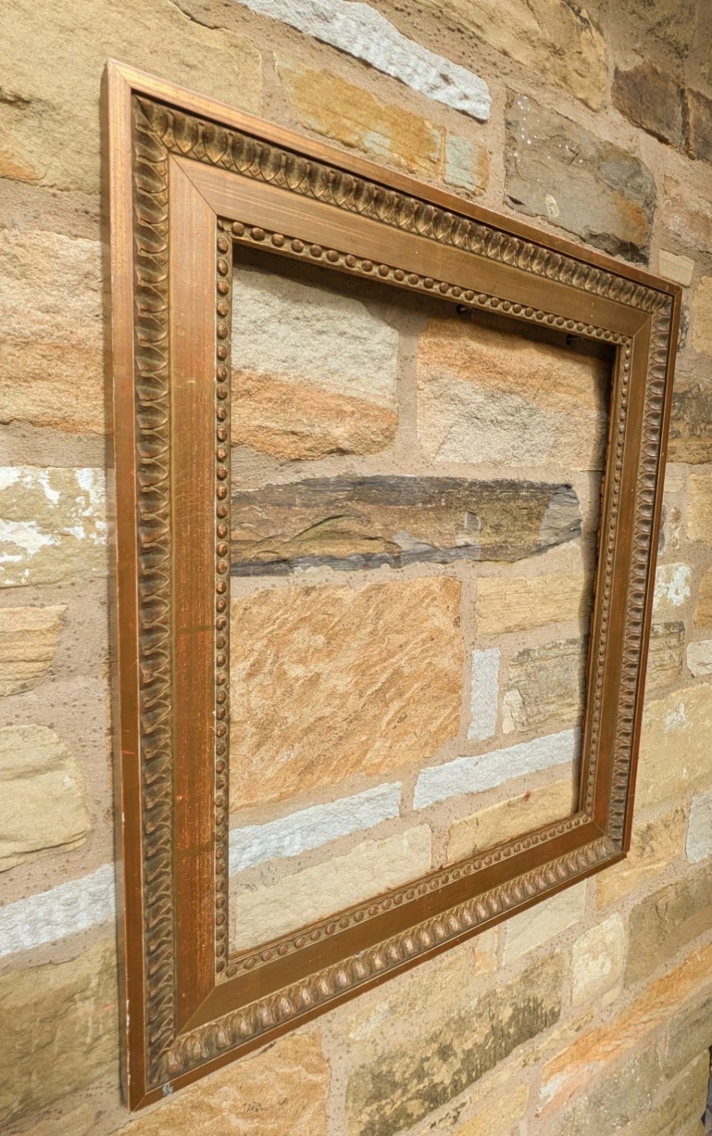 An early twentieth-century rectangular giltwood picture frame featuring classical egg and dart outer moulding and an inner beaded border. View II