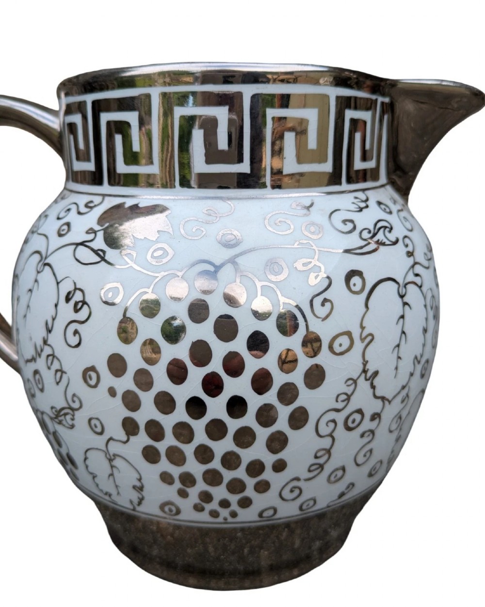 A white pearlware ceramic jug with silver lustre trim, featuring a Greek key band along the neck and a grape and vine pattern around the body. View V