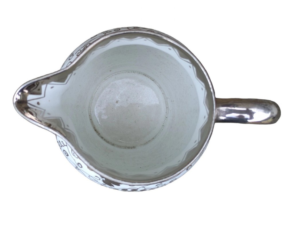 A white pearlware ceramic jug with silver lustre trim, featuring a Greek key band along the neck and a grape and vine pattern around the body. View VI