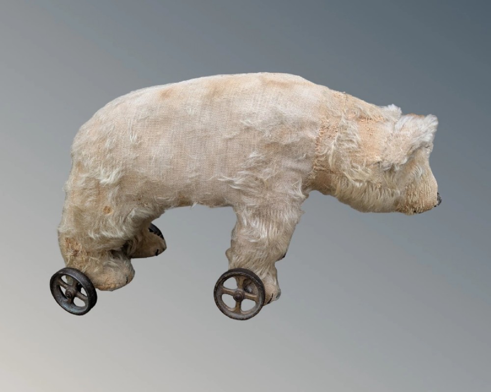 An early twentieth-century off-white mohair Steiff bear standing quadrupedally on four metal wheels. View III