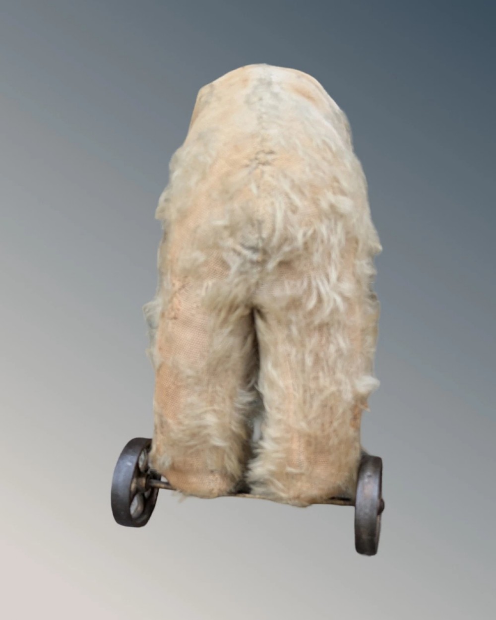 An early twentieth-century off-white mohair Steiff bear standing quadrupedally on four metal wheels. View V