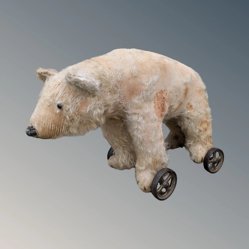 An early twentieth-century off-white mohair Steiff bear standing quadrupedally on four metal wheels. View VI